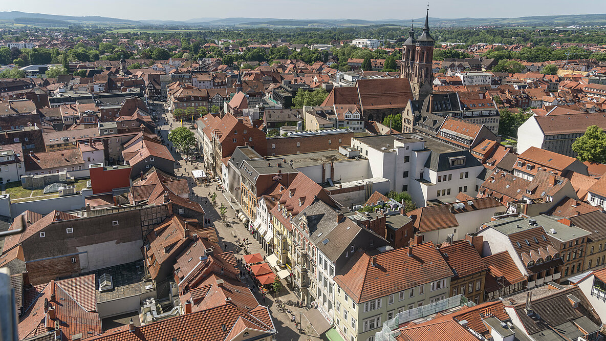 Ein Blick von oben auf eine Stadt, viele rote Dächer mit einem Kirchturm und einer Fußgängerzone.