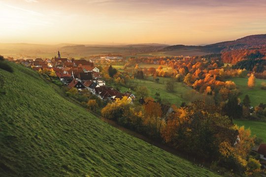 Eine Siedlung neben einem Berg, im Hintergrund geht die Sonne unter. 