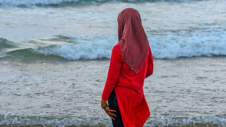 Junge Frau mit Kopftuch am Strand