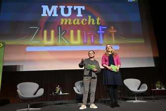 Die Co-Fraktionsvorsitzenden Katharina Dröge und Britta Haßelmann stehen gemeinsam auf einer Bühne und eröffnen den Kongress