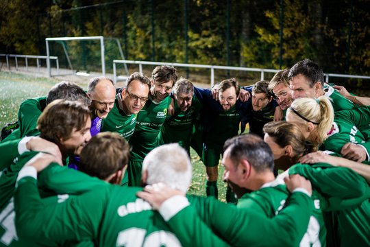 Männer in grünen Trikots stehen im Kreis und halten sich gegenseitig fest