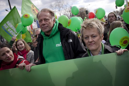 Jürgen Trittin und Renate Künast hinter einem grünen Banner. Um sie herum viele Menschen.