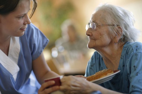 Eine Pflegerin und eine alte Frau in einem Pflegeheim, sie schauen sich an.