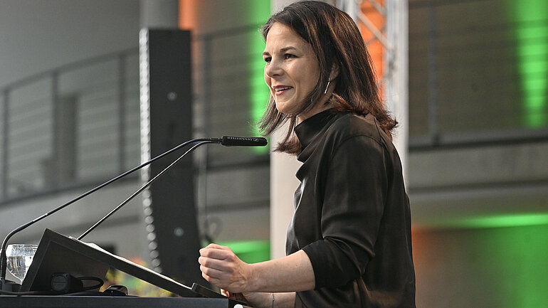 Annalena Baerbock, Bundesaußenministerin und Abgeordnete, steht auf einer Bühne und spricht in ein Mikrofon. 