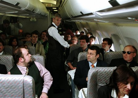 Joschka Fischer in einem Flugzeug mit anderen Mitreisenden.