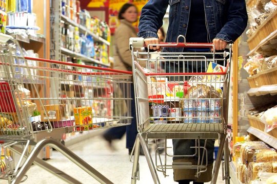 Zwei Personen schieben jeweils einen Einkaufswagen durch den Supermarkt. 